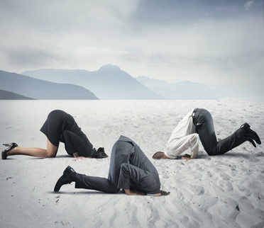 drei Leute in Businesskleidung stecken den Kopf in den Sand